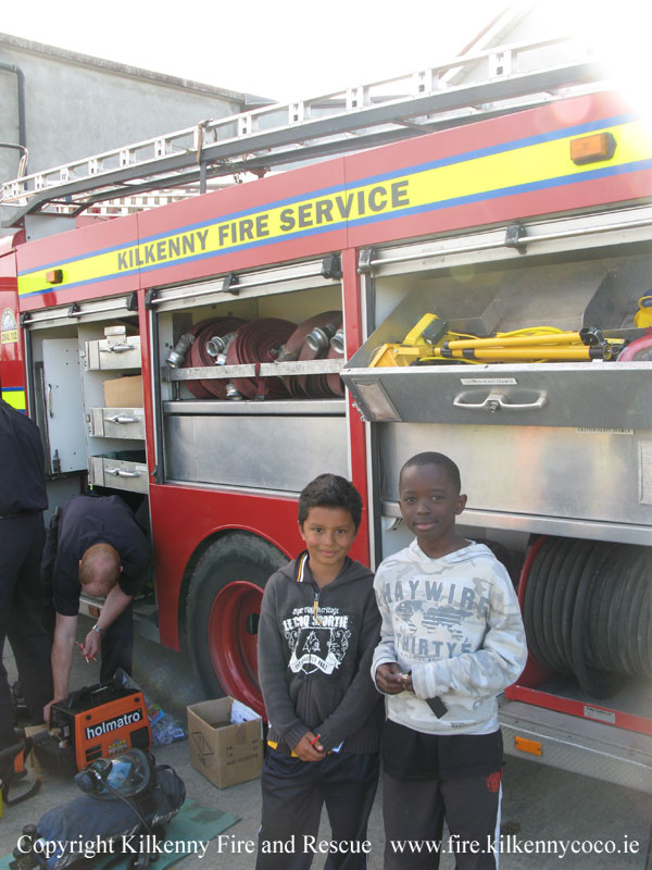 KCAN - Fireman works while children pose